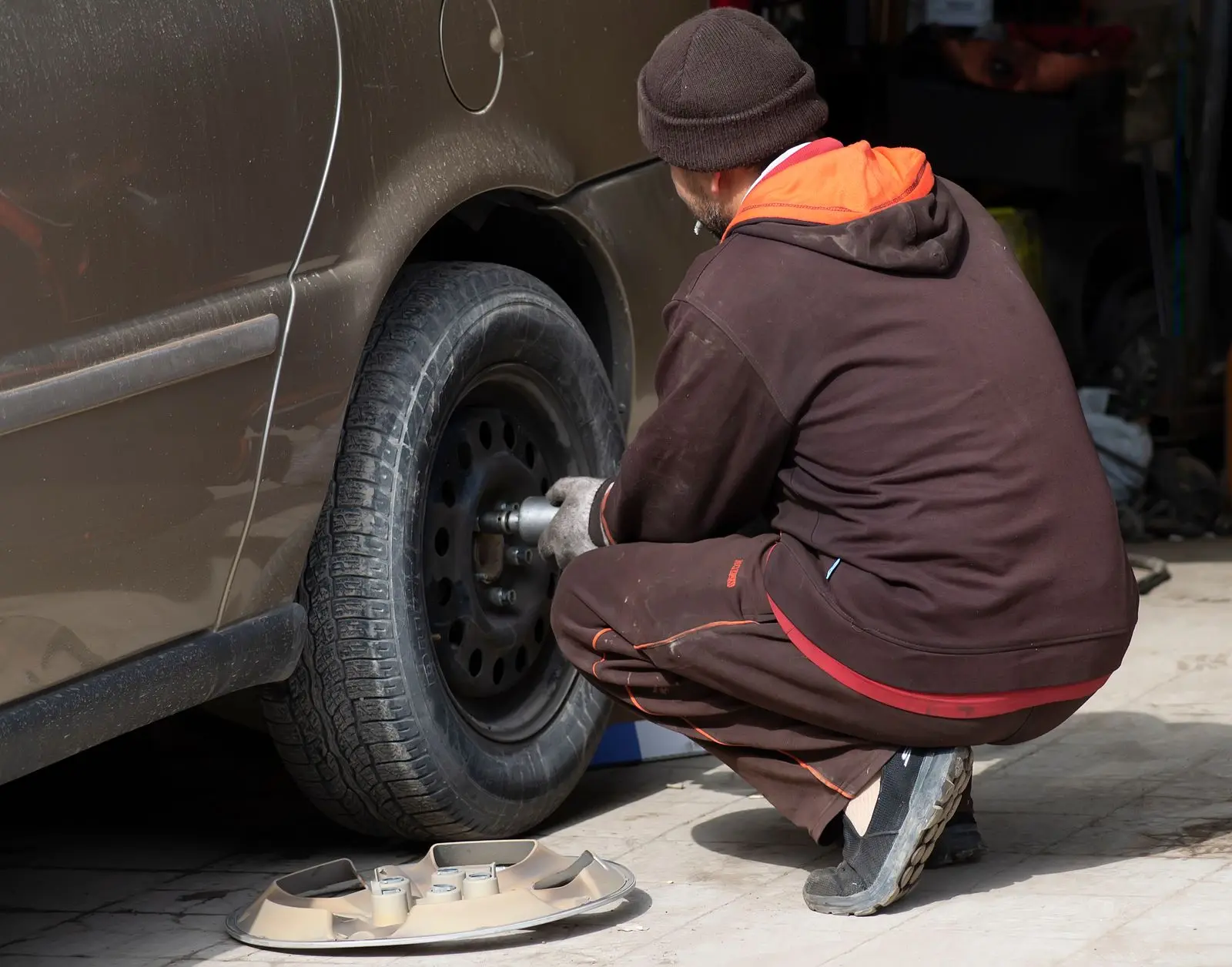 Mecánico cambia una rueda de automóvil con una herramienta. Imagen ilustrativa.